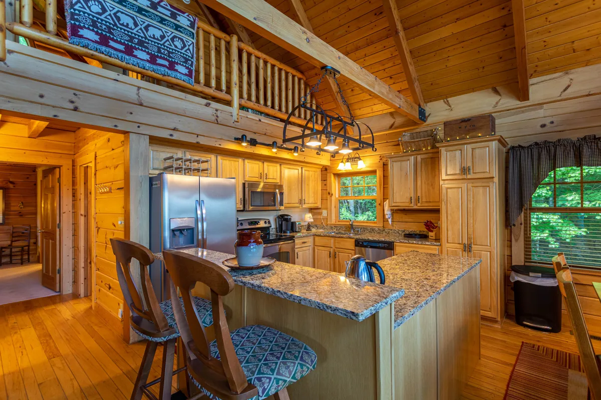 A warm, inviting kitchen featuring granite countertops, stainless steel appliances, and rich wooden cabinetry. The space is set up for cooking and entertaining, with plenty of room for preparing meals and gathering as a group.